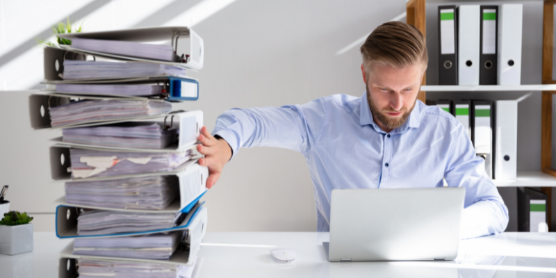 A man taking away paper documents and working on computer